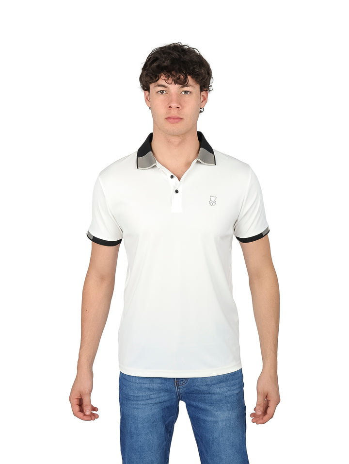 Hombre vistiendo playera polo blanca con detalles negros en el cuello y los bordes de las mangas.
