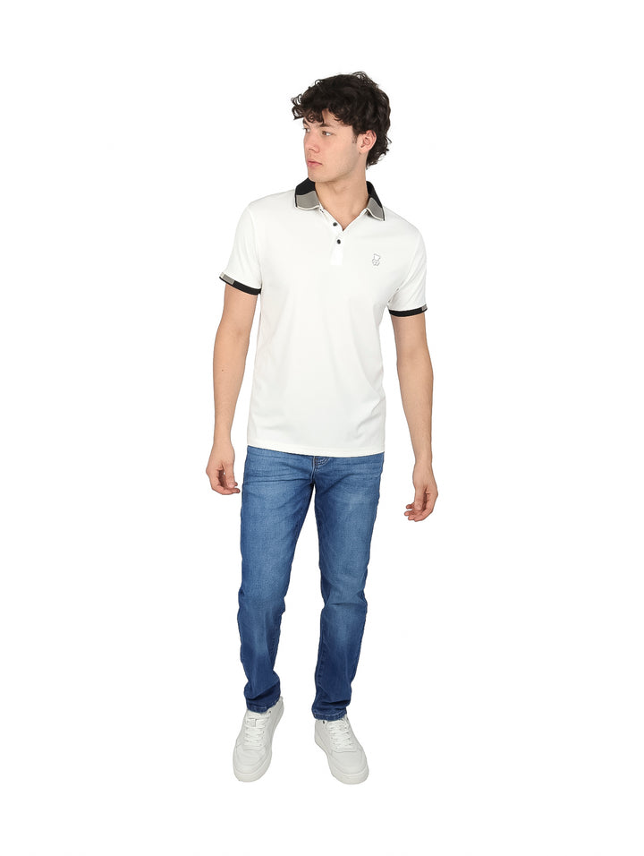 Hombre vistiendo playera polo blanca con detalles negros en el cuello y los bordes de las mangas.
