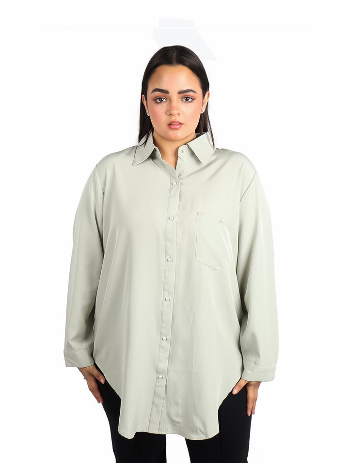 Mujer vistiendo camisa de color verde sage con manga larga y corte holgado.