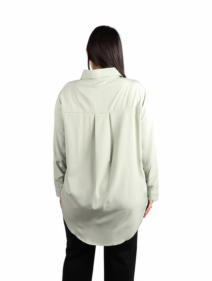 Mujer vistiendo camisa de color verde sage con manga larga y corte holgado.