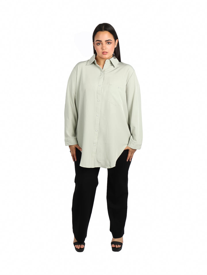 Mujer vistiendo camisa de color verde sage con manga larga y corte holgado.
