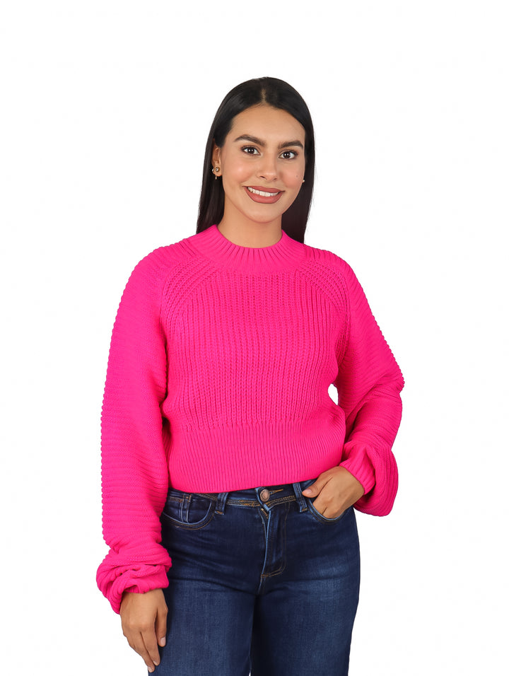 Mujer vistiendo un suéter rosa fucsia de manga bombacha y pantalones vaqueros azules.