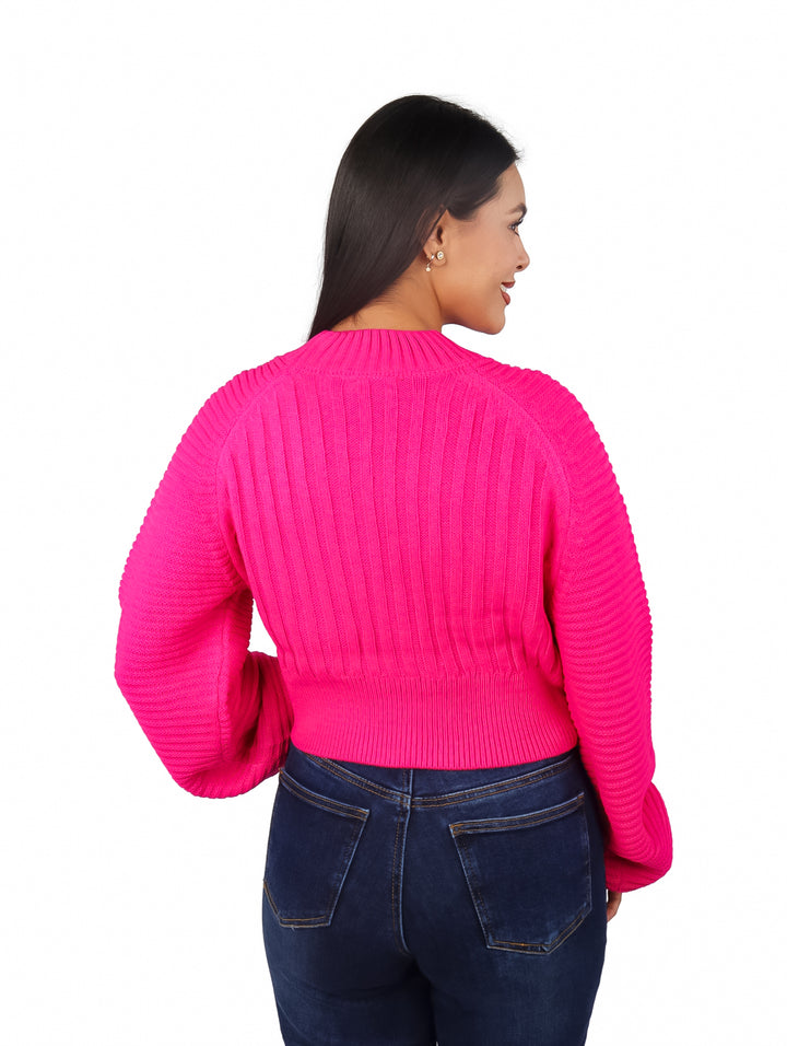 Mujer vistiendo un suéter rosa fucsia de manga bombacha y pantalones vaqueros azules.