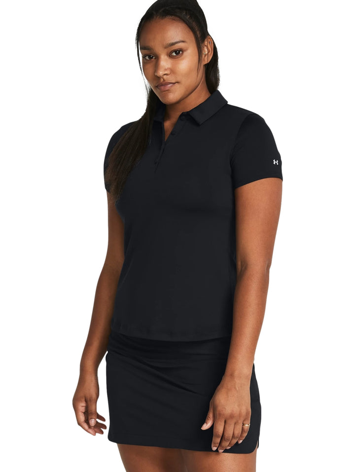 Mujer vistiendo polo deportiva Under Armour de color negro y falda a juego.