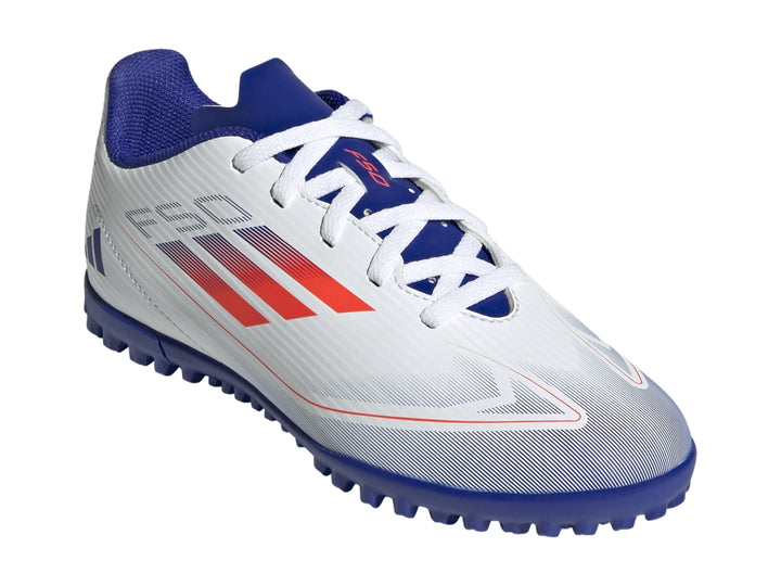 Zapato de fútbol Adidas F50 Club para niño, color blanco con suela azul y detalles en rojo.