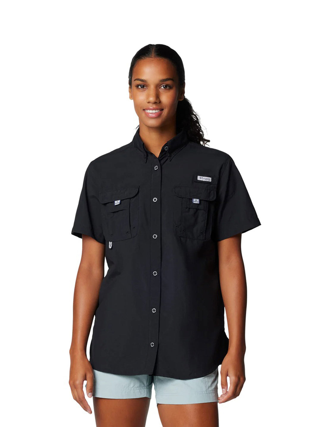 Mujer vistiendo una camisa Columbia de manga corta color negro con bolsillos frontales.