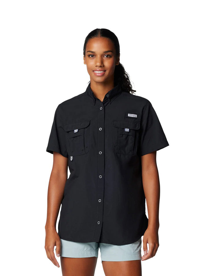Mujer vistiendo una camisa Columbia de manga corta color negro con bolsillos frontales.