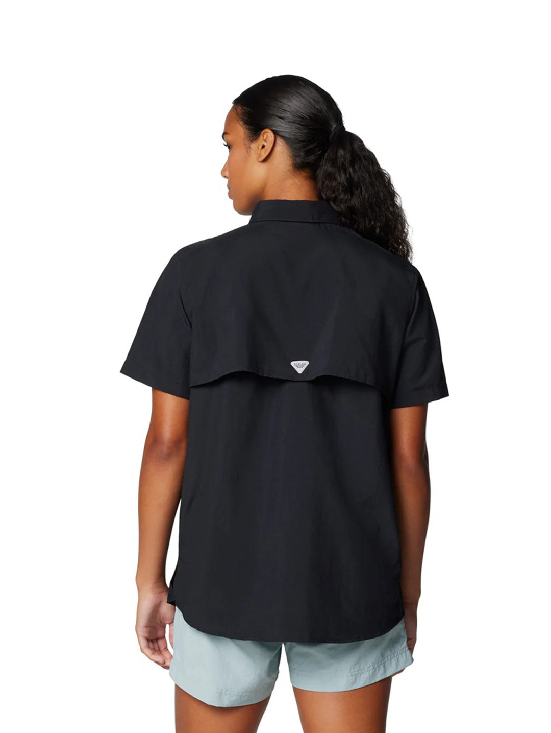 Mujer vistiendo una camisa Columbia de manga corta color negro con bolsillos frontales.