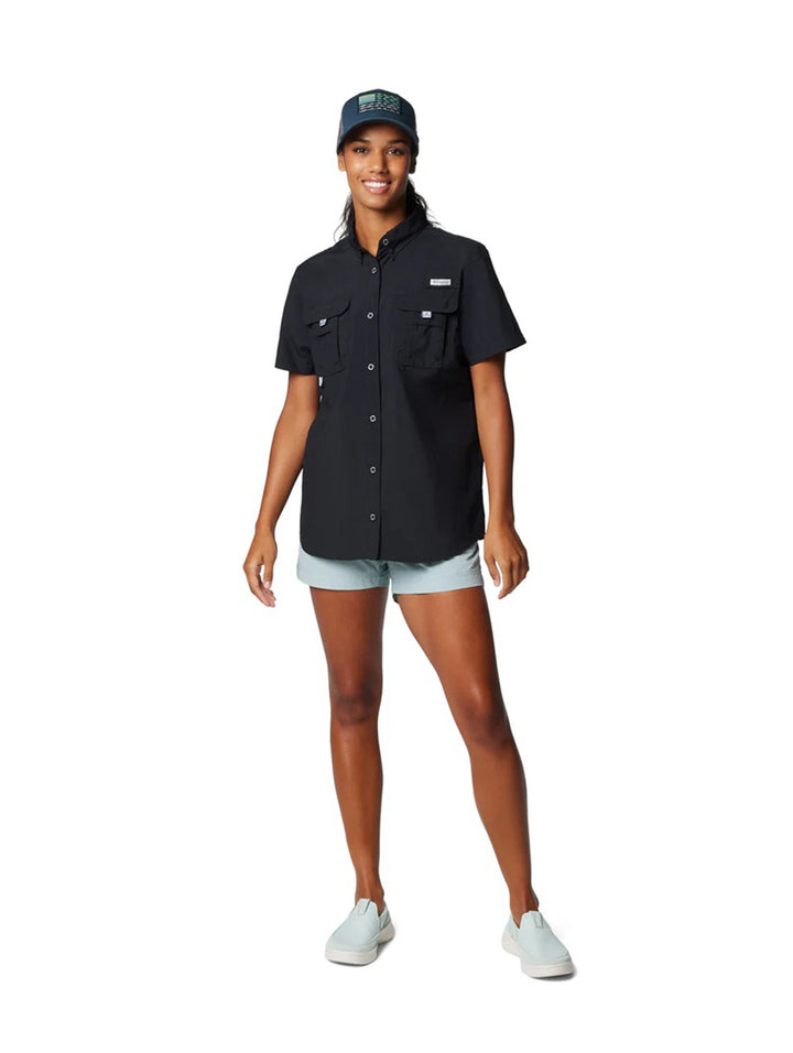Mujer vistiendo una camisa Columbia de manga corta color negro con bolsillos frontales.