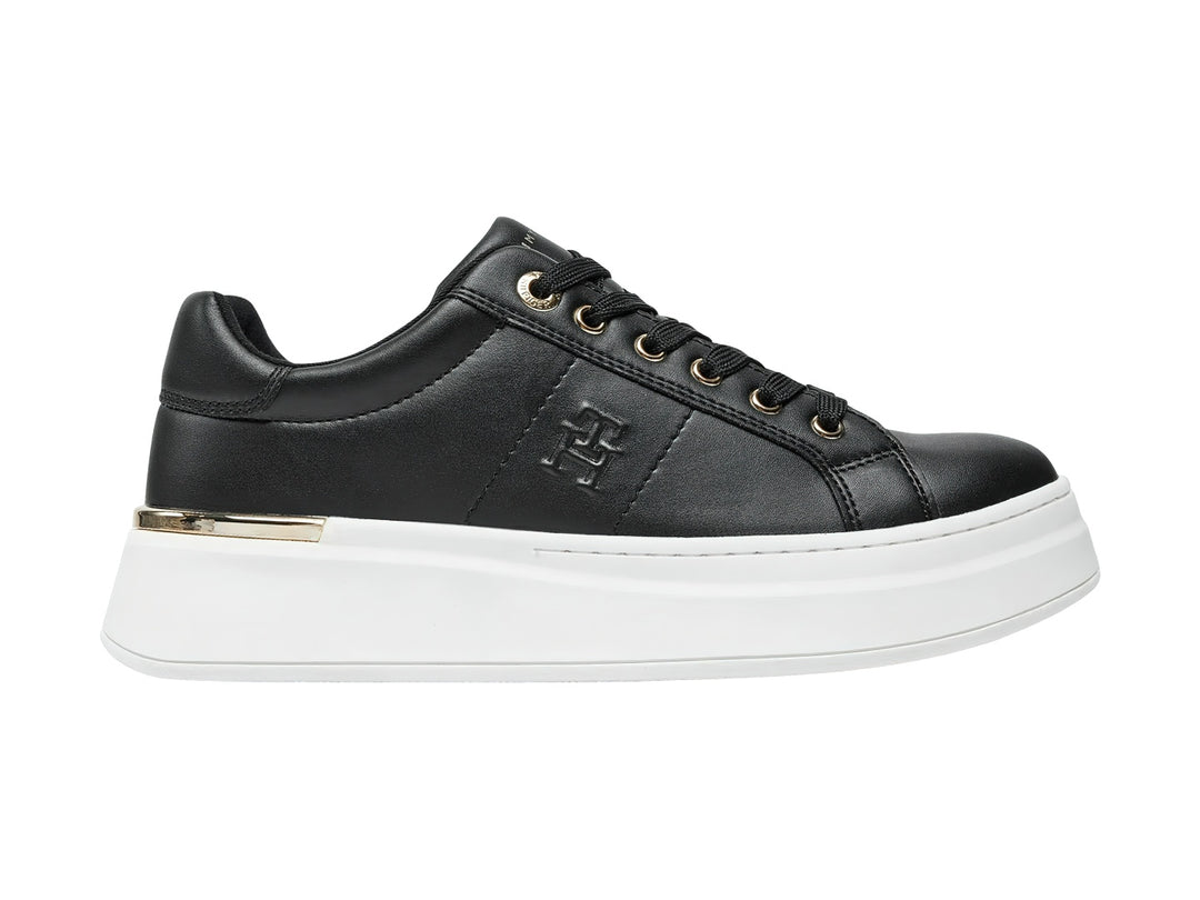 Tenis negros de corte bajo con suela blanca de plataforma y detalles dorados.