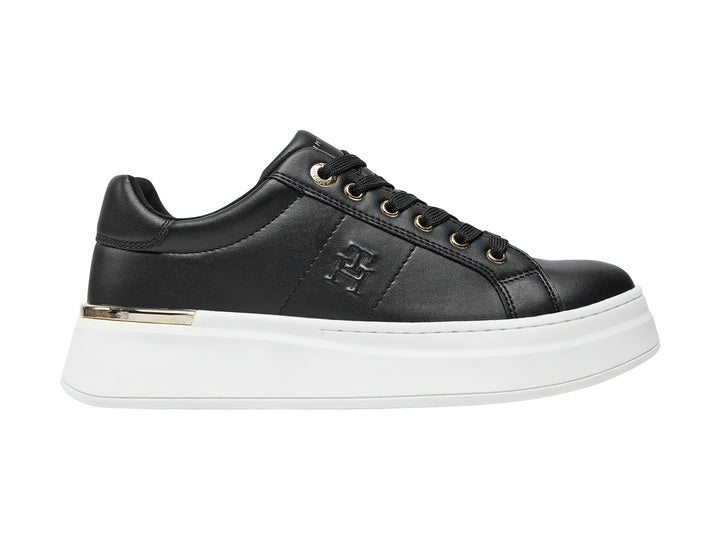 Tenis negros de corte bajo con suela blanca de plataforma y detalles dorados.