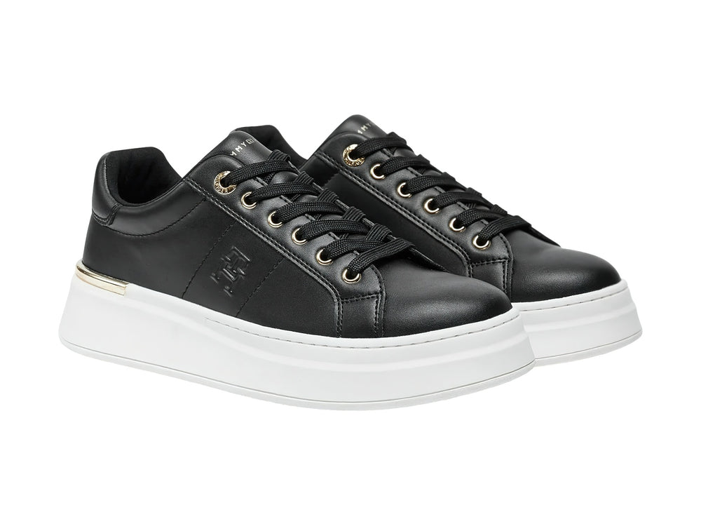 Tenis negros de corte bajo con suela blanca de plataforma y detalles dorados.