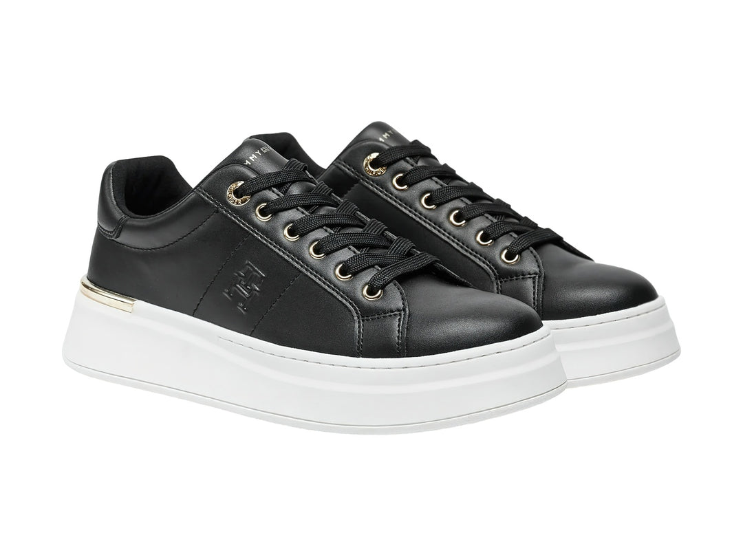 Tenis negros de corte bajo con suela blanca de plataforma y detalles dorados.