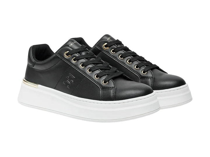 Tenis negros de corte bajo con suela blanca de plataforma y detalles dorados.