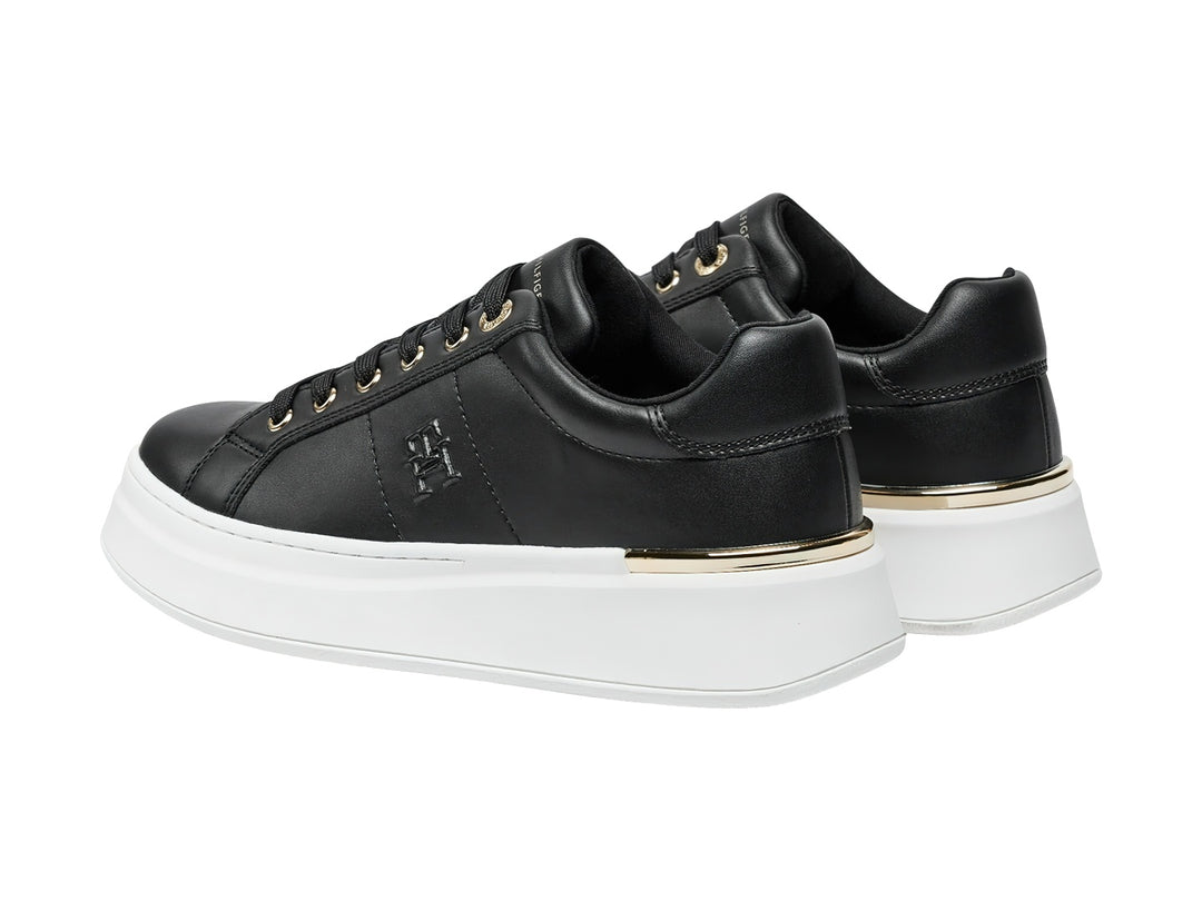 Tenis negros de corte bajo con suela blanca de plataforma y detalles dorados.
