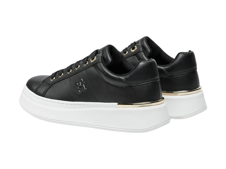 Tenis negros de corte bajo con suela blanca de plataforma y detalles dorados.