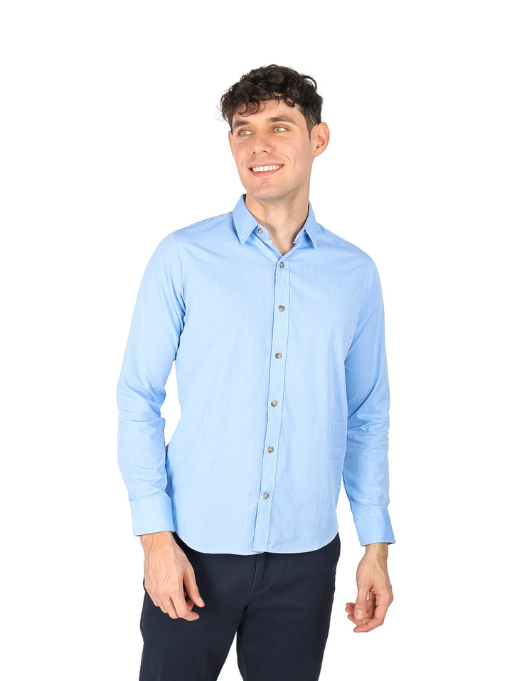 Hombre vistiendo una camisa lisa de color azul claro con manga larga y cuello.