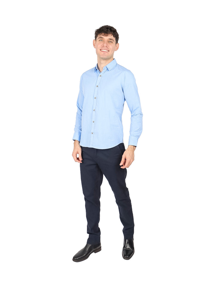 Hombre vistiendo una camisa lisa de color azul claro con manga larga y cuello.