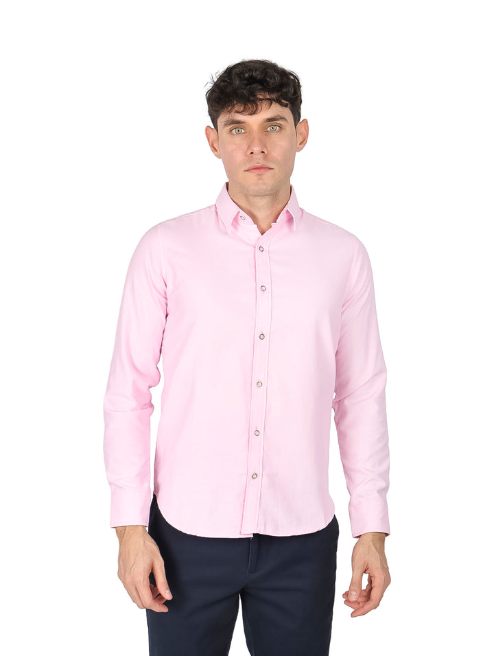 Hombre vistiendo una camisa de manga larga color rosa claro y pantalones azul marino.