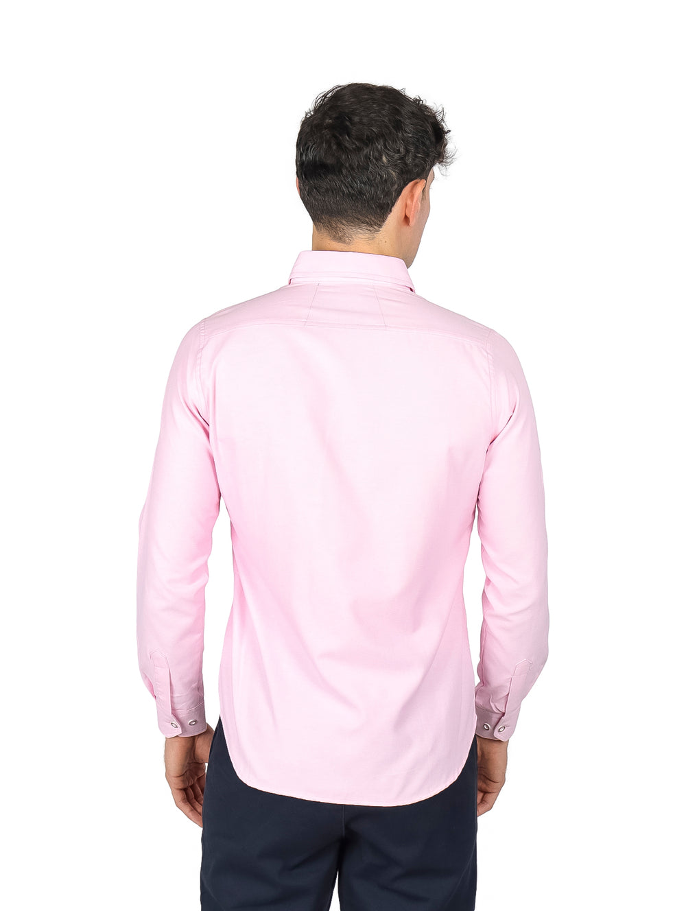 Hombre vistiendo una camisa de manga larga color rosa claro y pantalones azul marino.