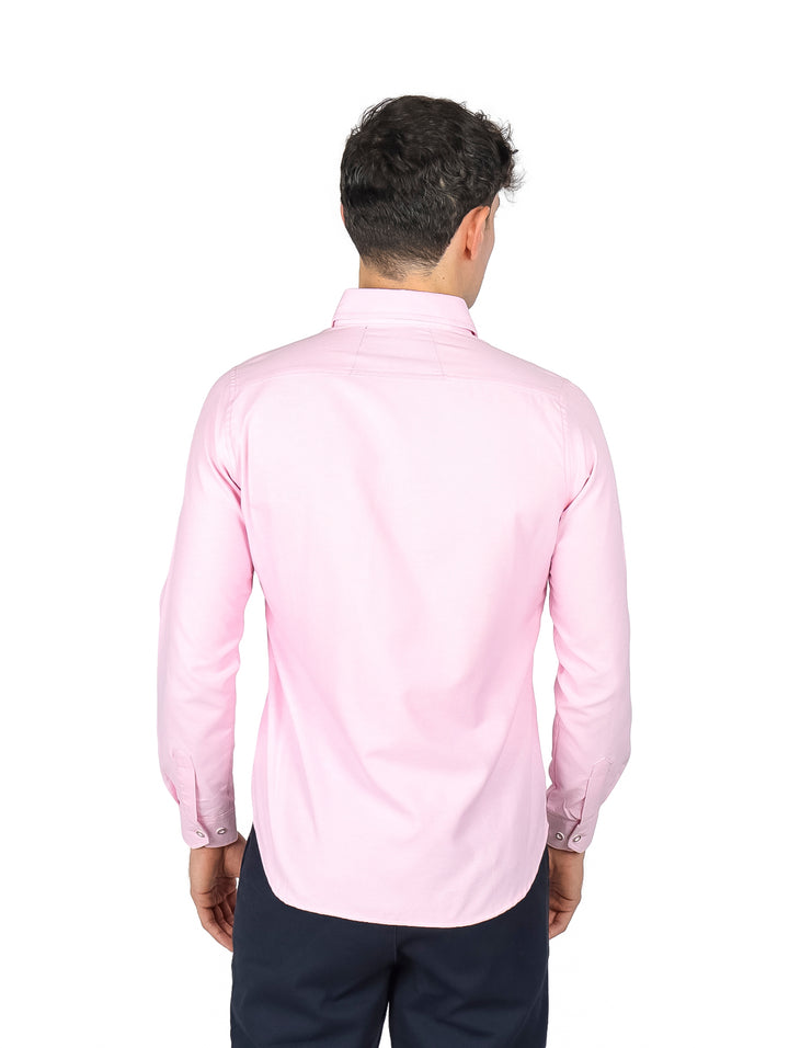 Hombre vistiendo una camisa de manga larga color rosa claro y pantalones azul marino.
