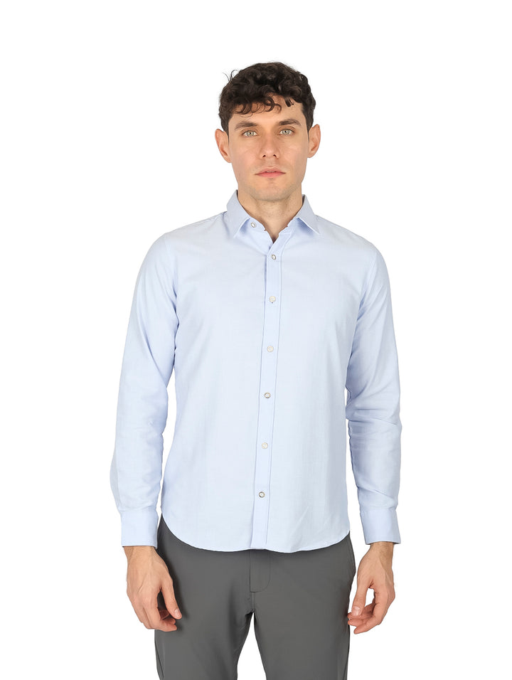 Hombre vistiendo una camisa de manga larga color azul cielo lisa.
