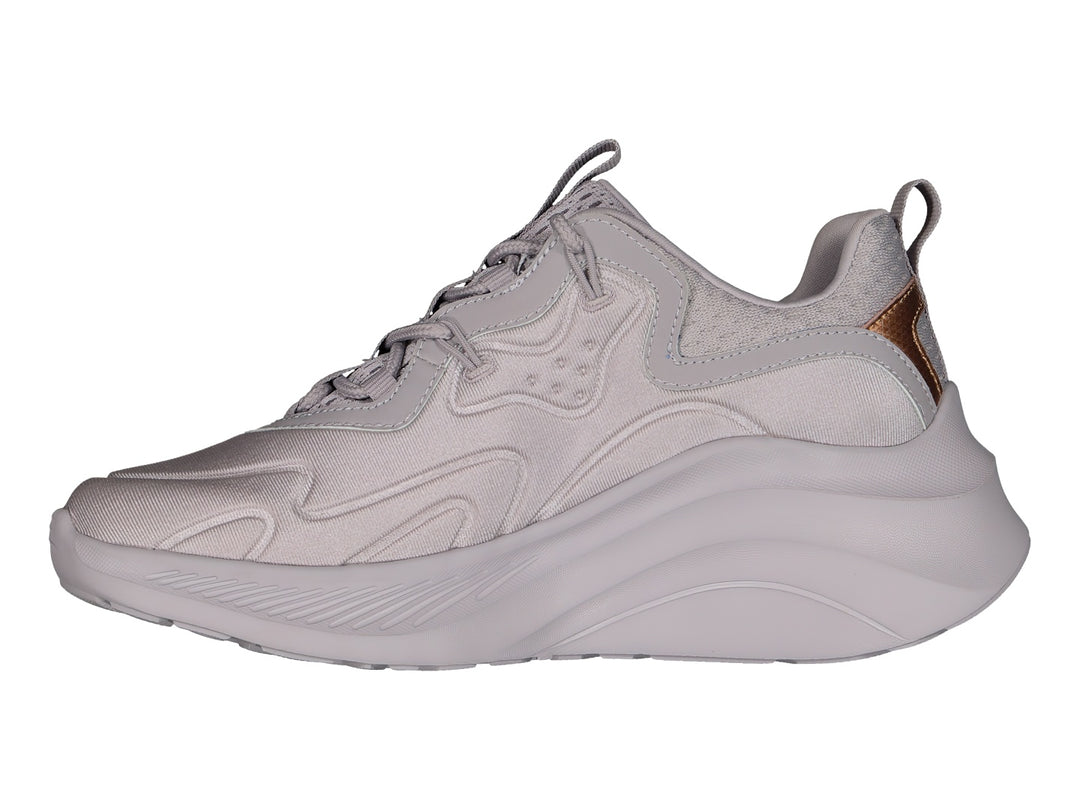 Tenis Skechers color lavanda con suela gruesa y detalles metálicos en oro rosa.