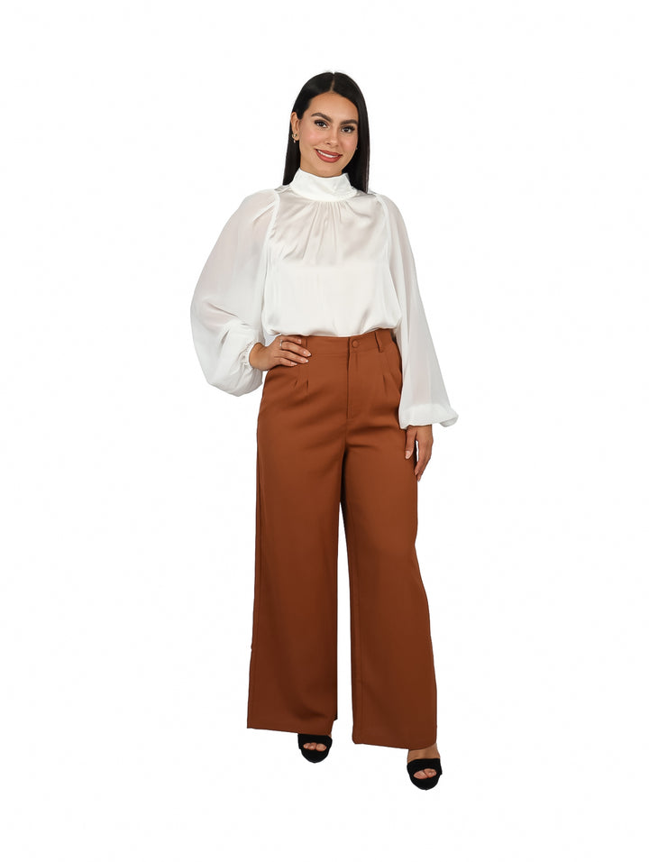 Mujer vistiendo blusa color ivory de cuello alto y mangas largas con acabado brillante.