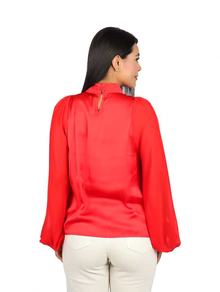 Mujer vistiendo una blusa roja de manga larga y cuello alto sobre fondo blanco.