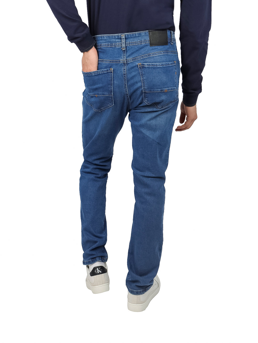 Hombre vistiendo pantalón de mezclilla azul estilo stone con corte recto y calzado blanco.