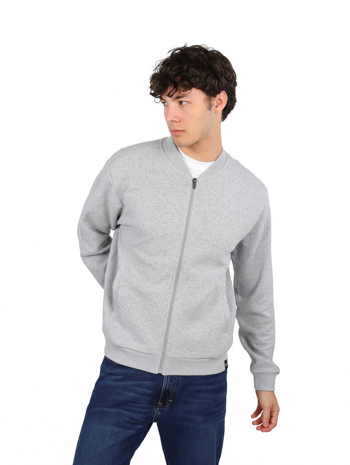 Hombre vistiendo una sudadera gris con cierre frontal y cuello redondo.