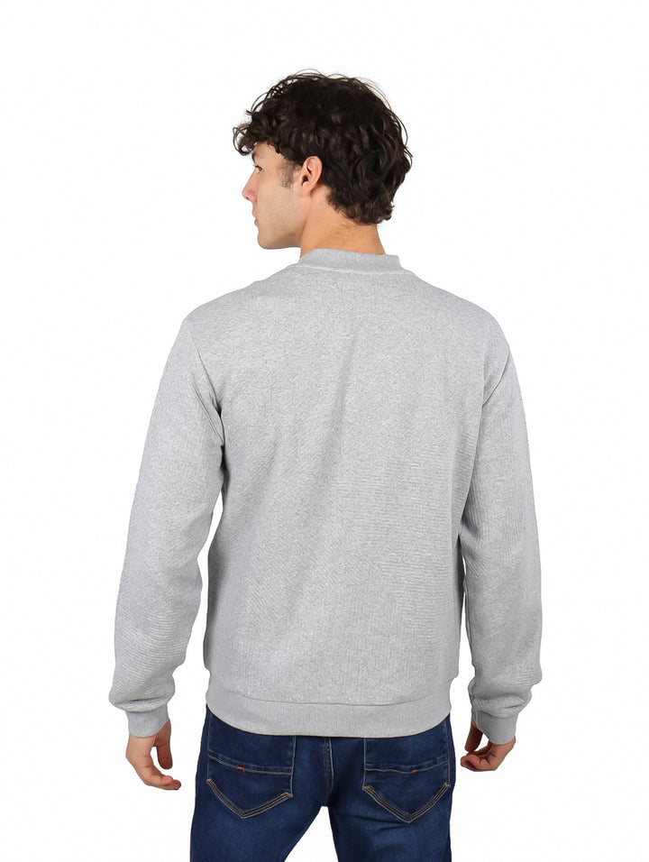 Hombre vistiendo una sudadera gris con cierre frontal y cuello redondo.