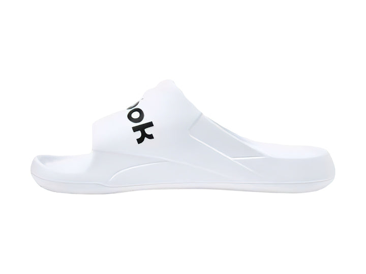Sandalia deslizante Reebok de color blanco con logotipo negro en la banda superior.