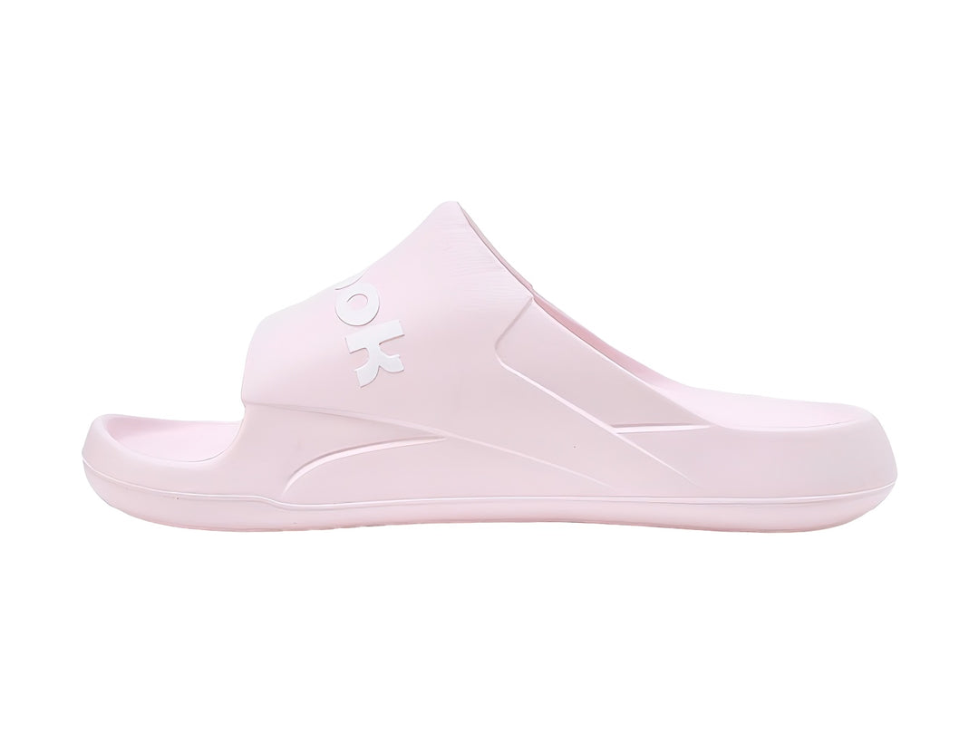 Sandalias slide Reebok en color rosa pálido con logotipo blanco en la banda superior.