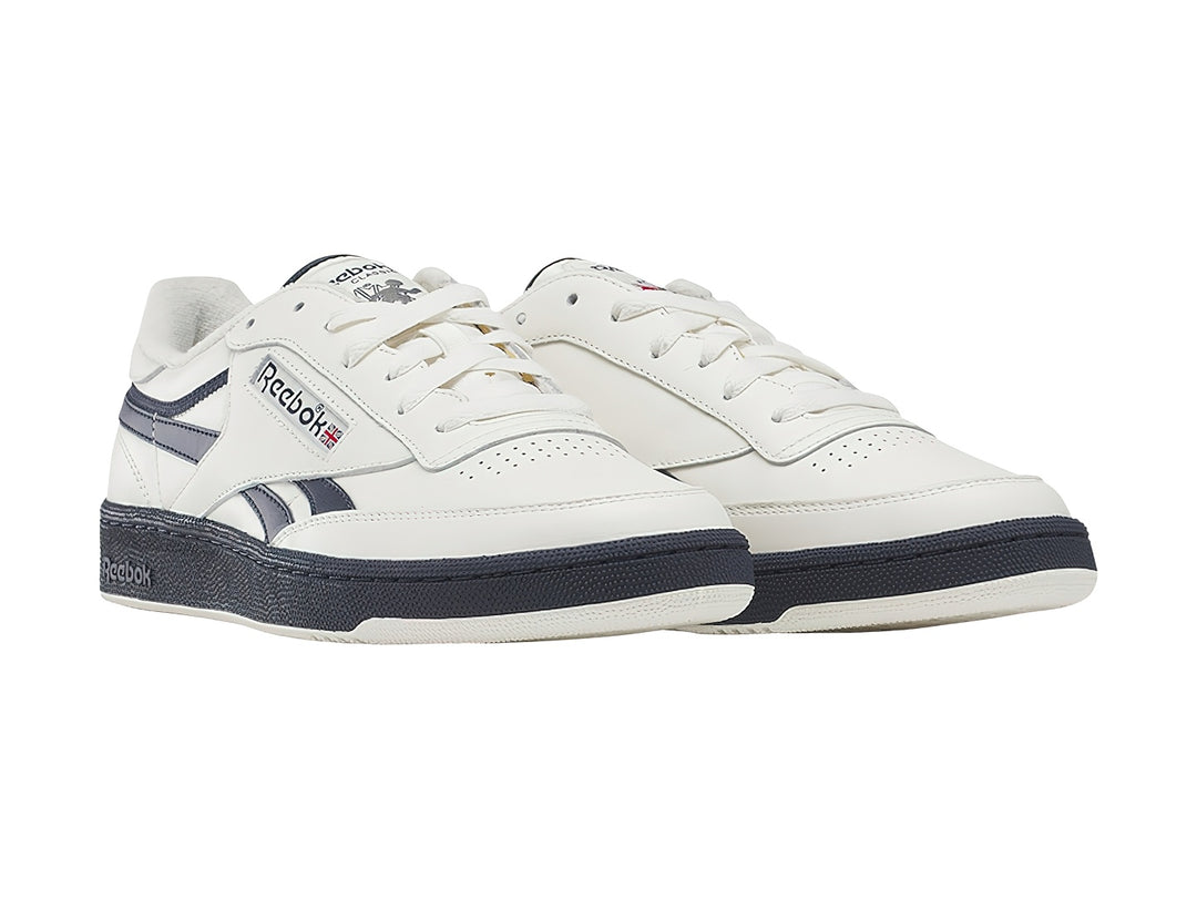 Tenis Reebok blancos con detalles y suela azul marino, estilo vintage.