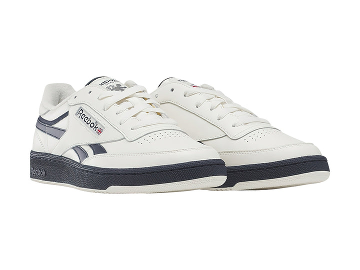 Tenis Reebok blancos con detalles y suela azul marino, estilo vintage.