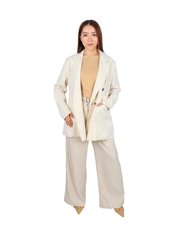 Mujer vistiendo un saco blazer color beige con botones oscuros y pantalones a juego.