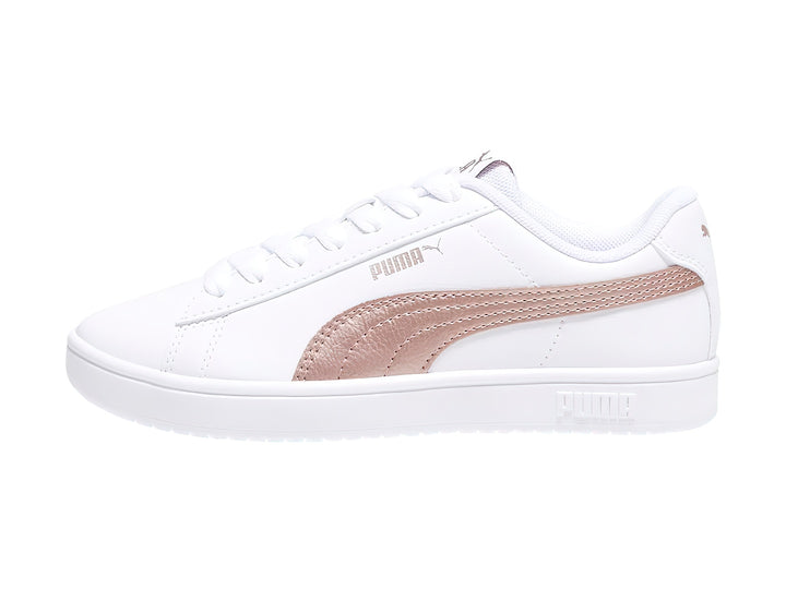 Tenis PUMA Rickie Classic Jr en color blanco con franja lateral en tono oro rosa y suela blanca.