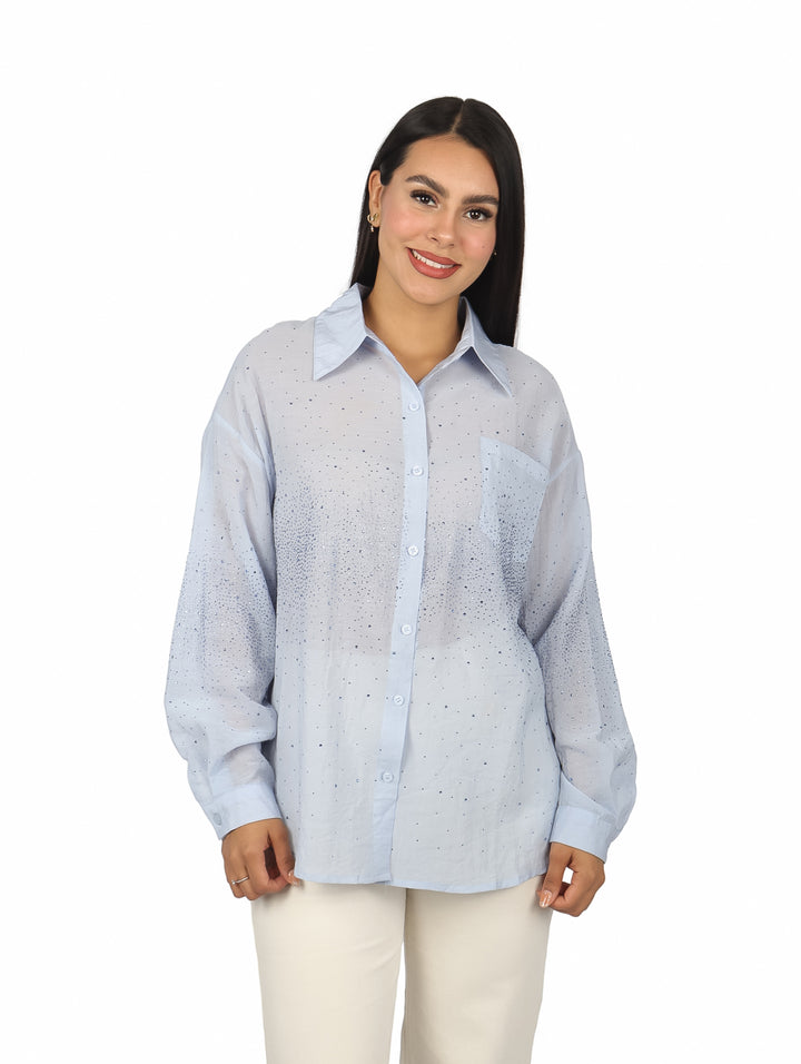 Mujer vistiendo una camisa de maternidad color azul claro con manga larga y detalles de pequeñas piedras brillantes.