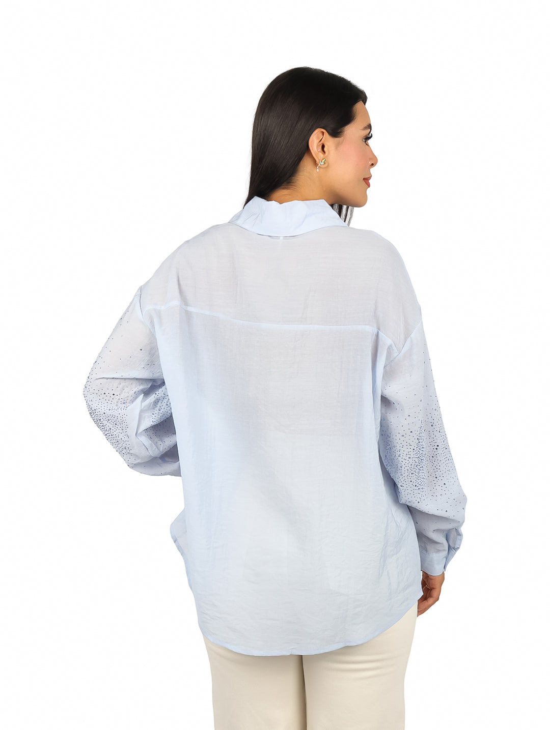 Mujer vistiendo una camisa de maternidad color azul claro con manga larga y detalles de pequeñas piedras brillantes.