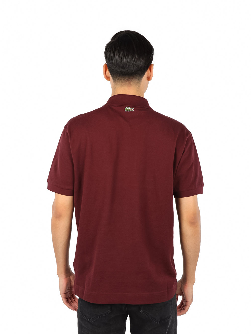 Hombre vistiendo una playera polo Lacoste de color bordeaux con cuello y manga corta.