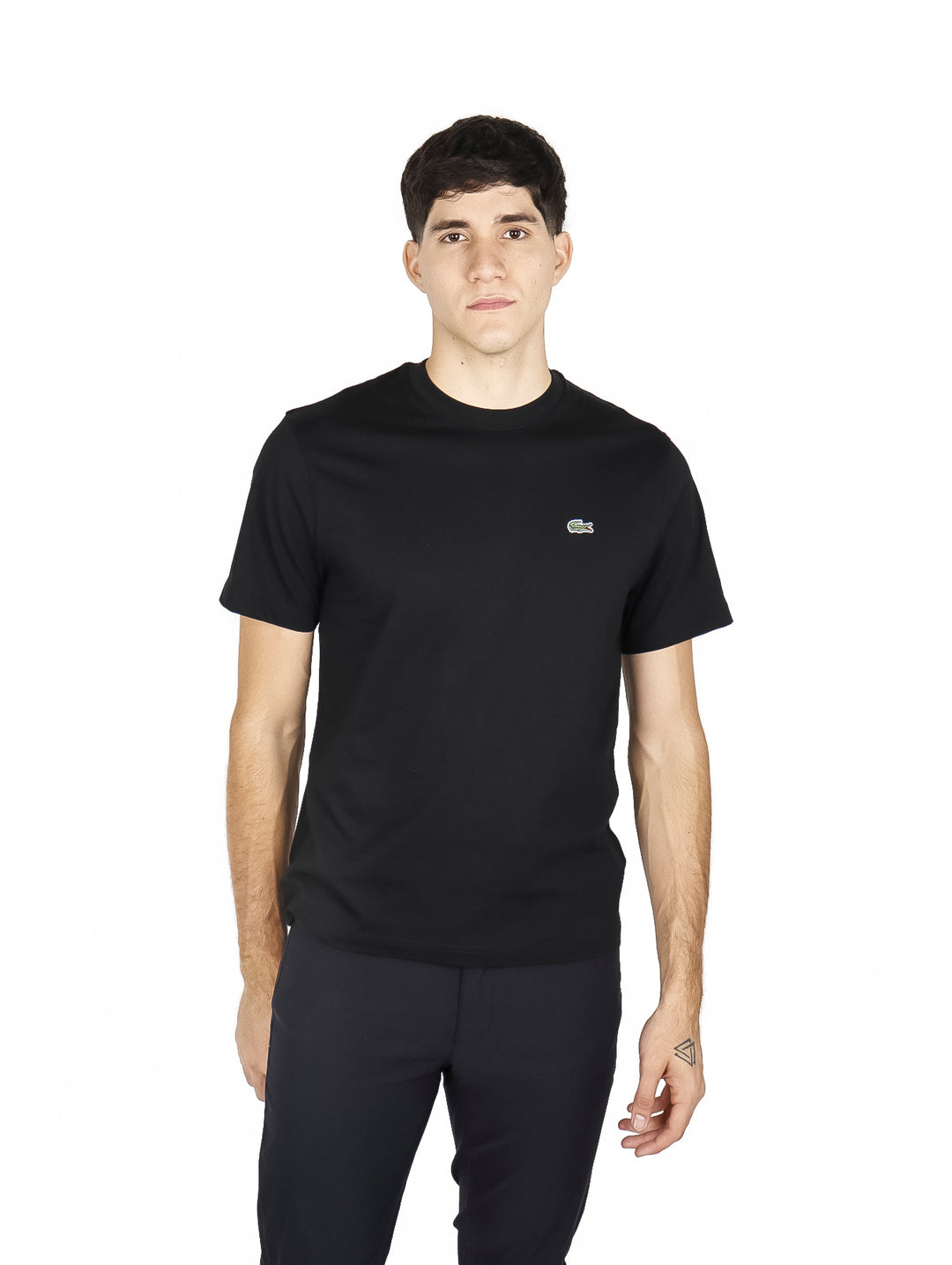 Hombre vistiendo una camiseta de manga corta color negro de la marca Lacoste.