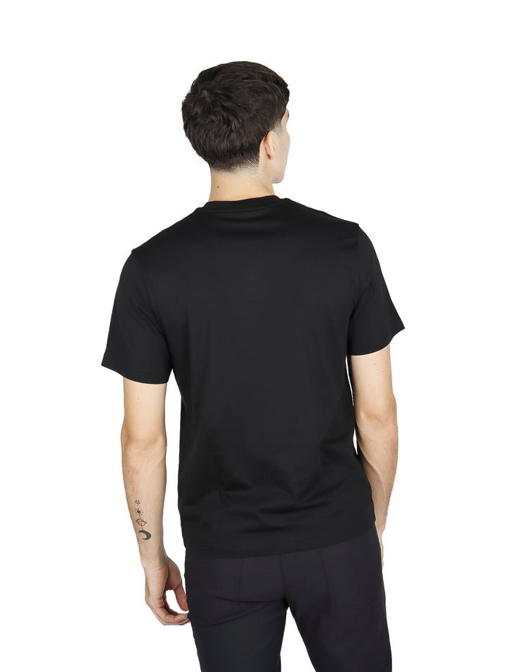 Hombre vistiendo una camiseta de manga corta color negro de la marca Lacoste.