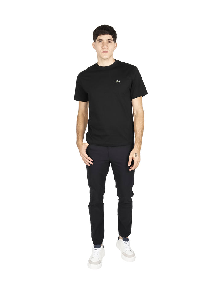 Hombre vistiendo una camiseta de manga corta color negro de la marca Lacoste.