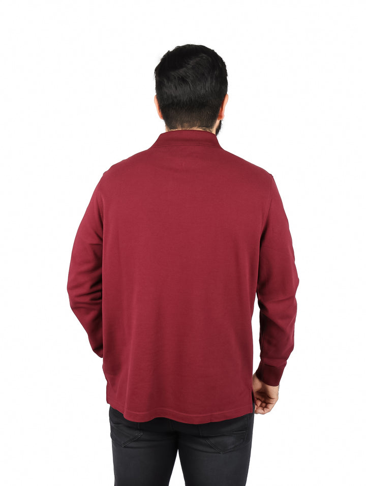 Hombre vistiendo una playera polo de manga larga color rojo oscuro de la marca Tommy Hilfiger.