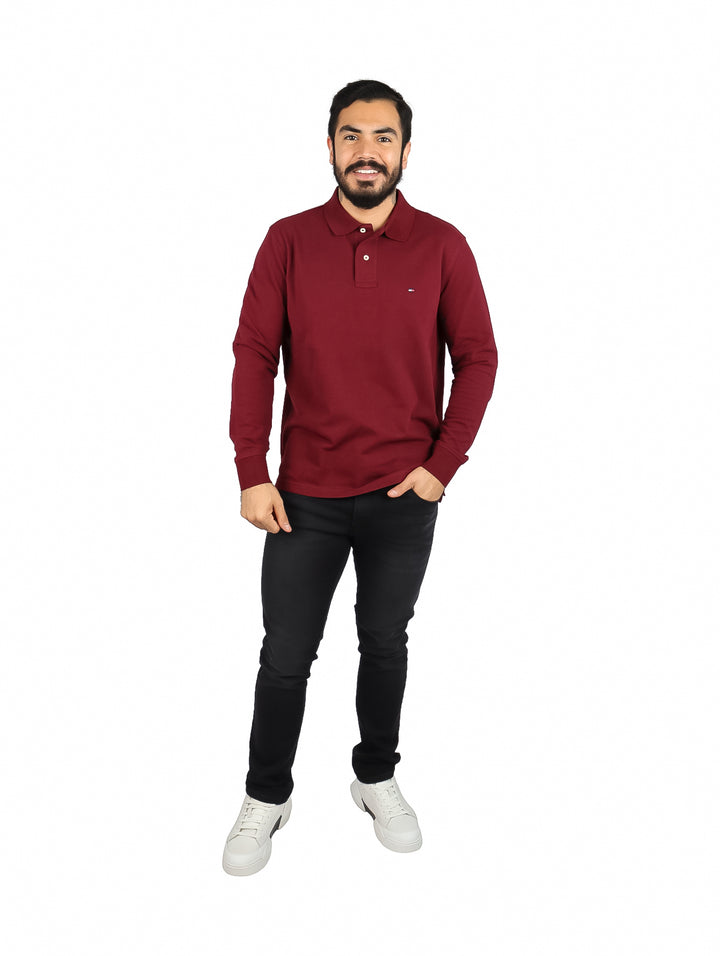 Hombre vistiendo una playera polo de manga larga color rojo oscuro de la marca Tommy Hilfiger.