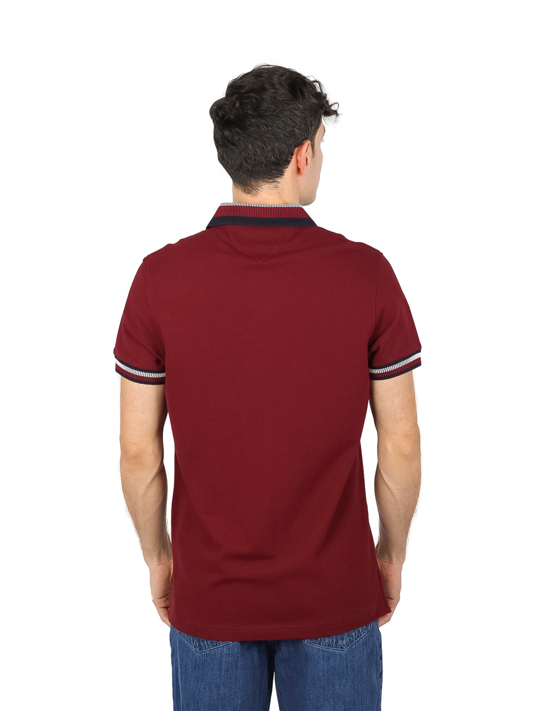 Hombre vistiendo una playera polo Tommy Hilfiger de color rojo oscuro con detalles en el cuello y mangas.