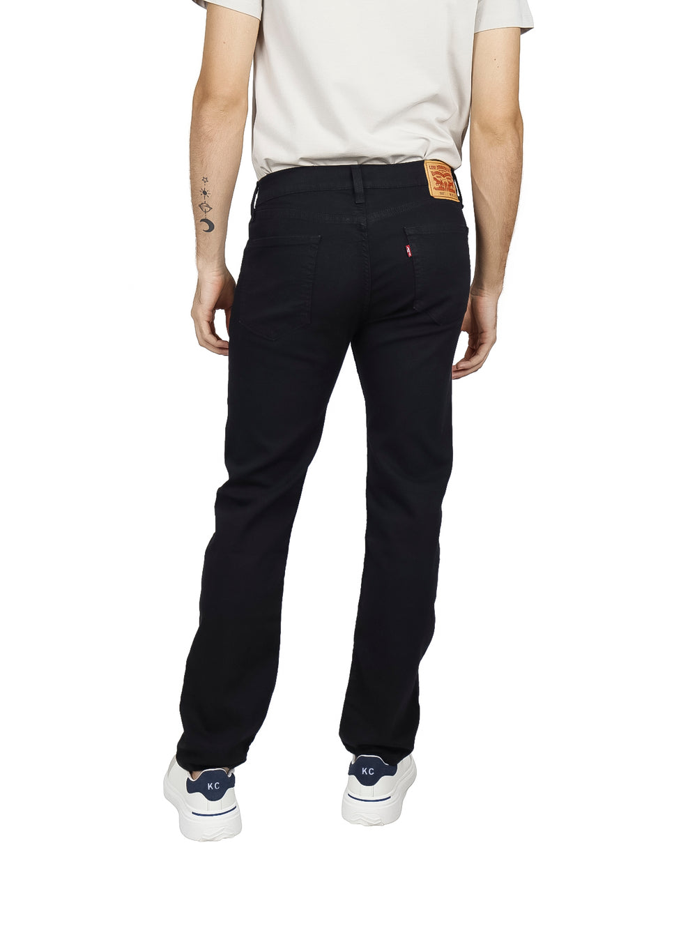 Hombre vistiendo pantalones Levi's 505 de color negro, corte regular fit, con camiseta clara y tenis blancos.