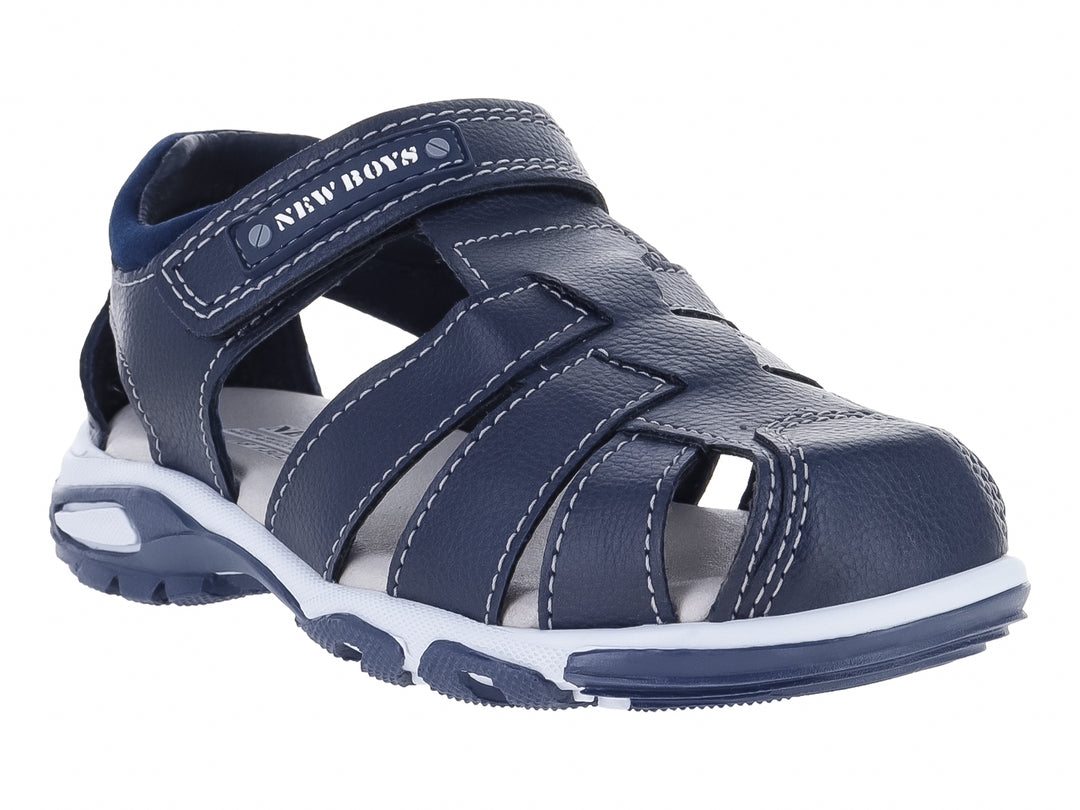 Sandalia cerrada para niño en color azul marino con suela blanca y ajuste de velcro.