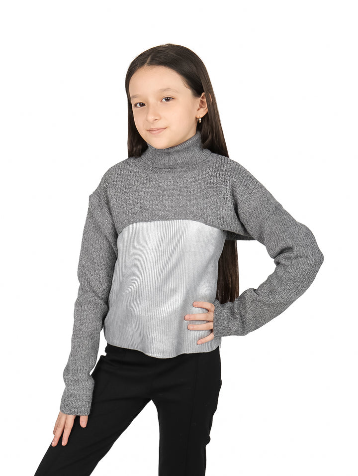 Niña vistiendo blusa de cuello alto en colores gris y plateado con pantalones negros.